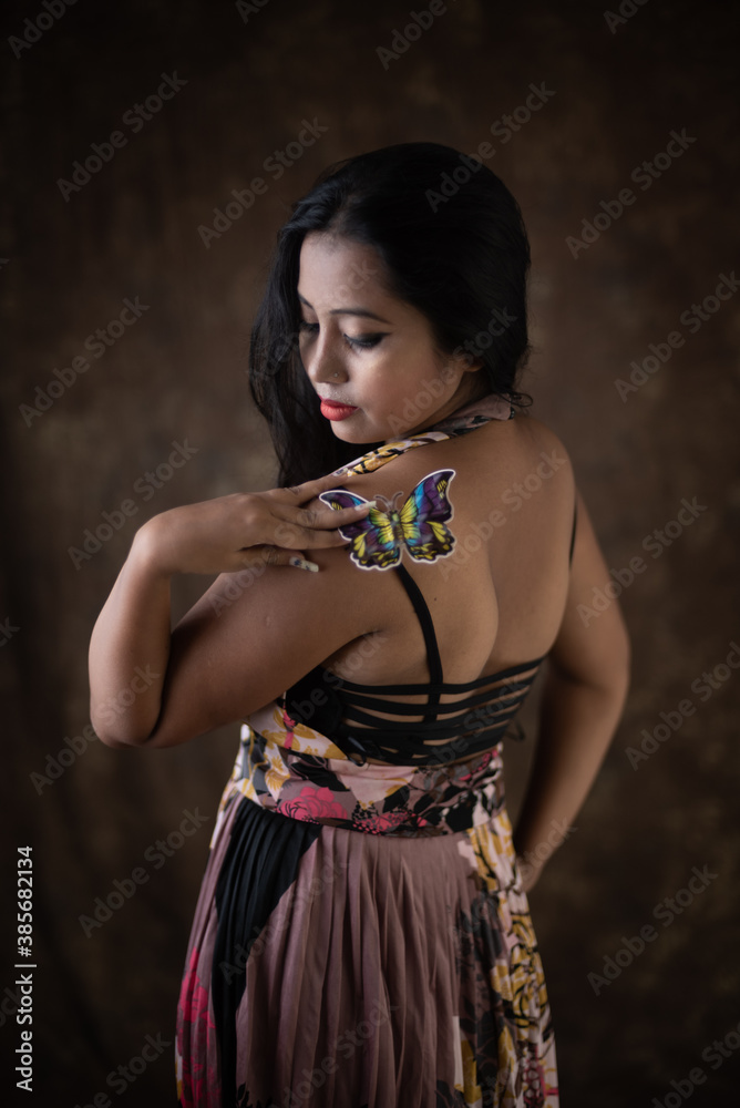 Studio portrait of an young Indian girl in western backless dress in front of textured background. Fashion portrait photography