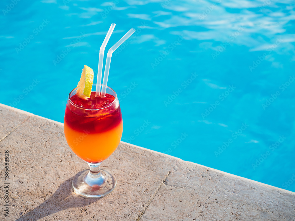 Obraz premium Beautiful glass with a cocktail on the background of the pool. View from above, close-up. Concept of leisure and travel