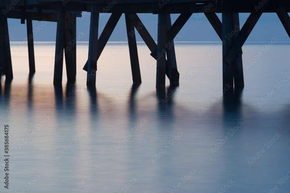 The scenery of a long exposure of the wooden bridge in sunset time.