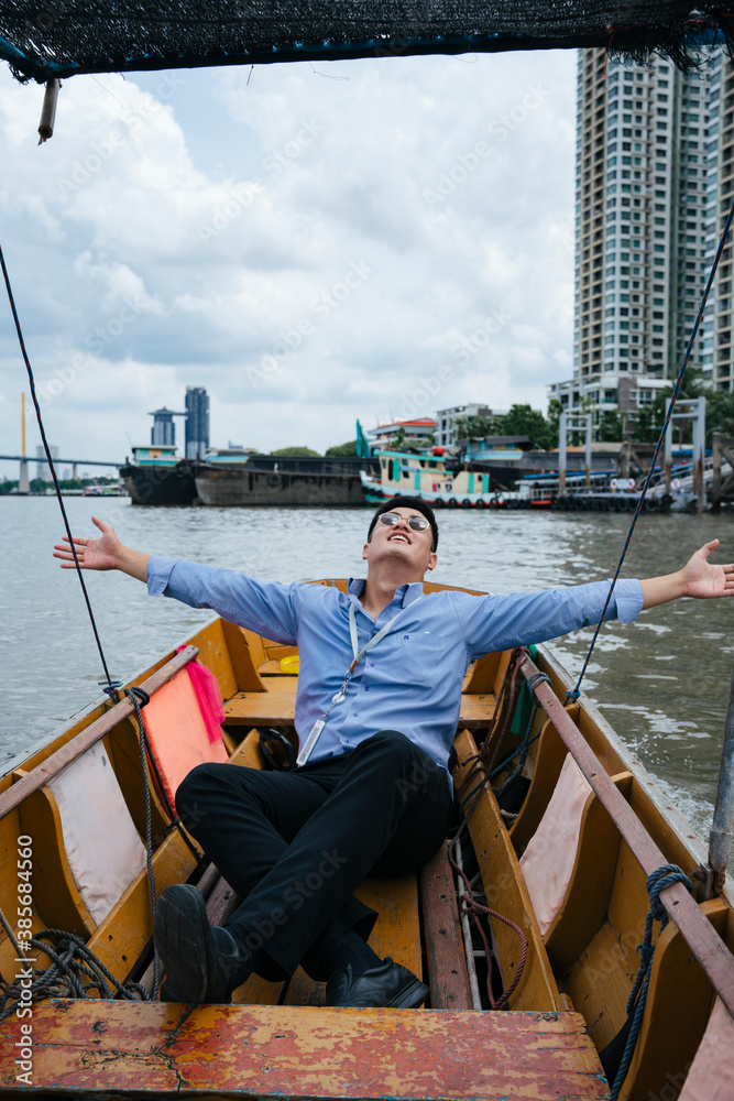 Business man wear sunglasses sitting on a boat in Bangkok.