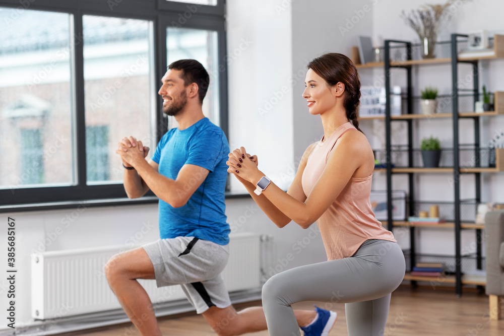 sport, fitness, lifestyle and people concept - smiling man and woman exercising and doing squats in low lunge at home sport, fitness, lifestyle and people concept - smiling man and woman exercising and doing squats in low lunge at home