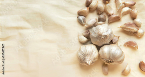 Top view Garlic bulb and garlic cloves on crumpled warm beige background with copy space