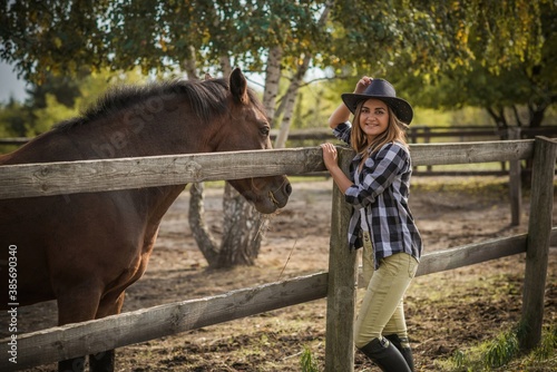 American woman on a horse farm. Portrait of girl in cowboy hat with a horses. Hippotherapy at nature