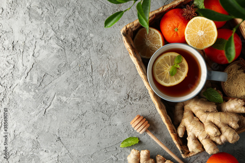 Basket with ginger, orange, cinnamon, lemon and tea on gray background
