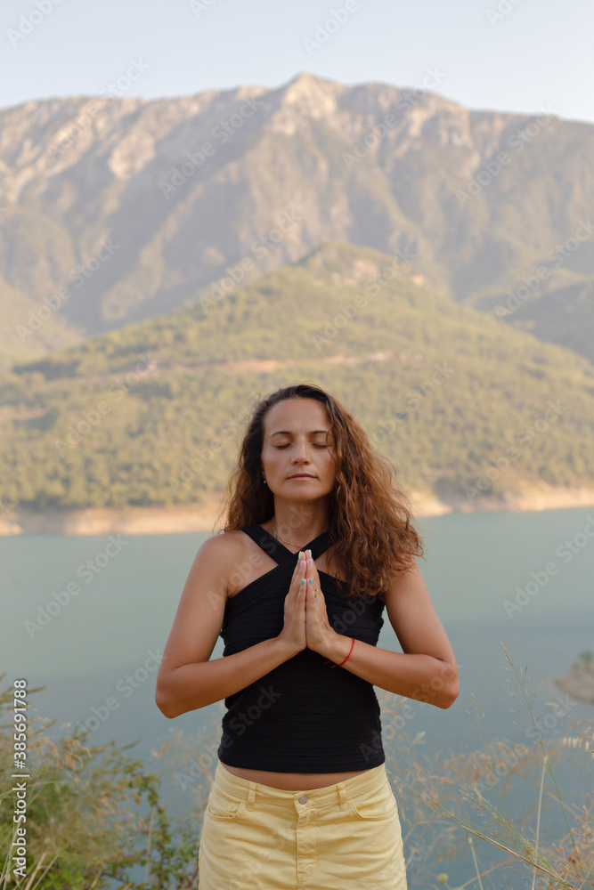 Woman in her thirties, hands in namaste with eyes closed Woman in her thirties, hands in namaste with eyes closed