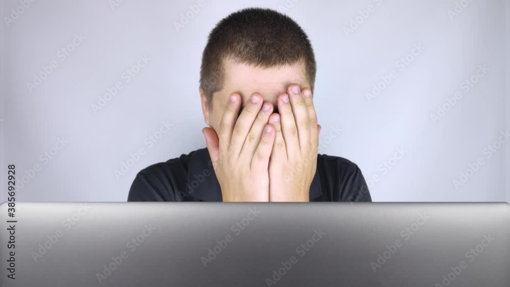 The man looks at the laptop, is embarrassed and ashamed of what he saw there. Expressing emotions and reacting to what you see on the Internet. Shocking content concept. The man looks at the laptop, is embarrassed and ashamed of what he saw there. Expressing emotions and reacting to what you see on the Internet. Shocking content concept.