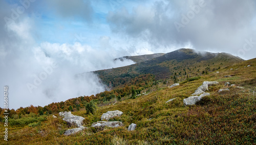 Thick fog in the autumn mountains. The mountain slopes disappear into a white veil