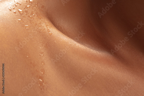 Close up of female neck and shoulder with water drops in beautiful shine. African-american model. Beauty, fashion, skincare, cosmetics concept. Copyspace for ad. Well-kept skin, fresh look.