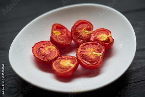 Grilled baked tomatoes in the oven on a white plate.