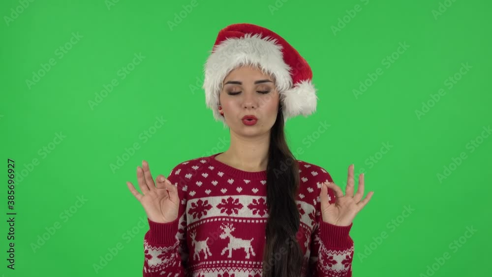 Portrait of sweety girl in Santa Claus hat is refusing stress and taking situation, calming down. Green screen Portrait of sweety girl in Santa Claus hat is refusing stress and taking situation, calming down. Green screen