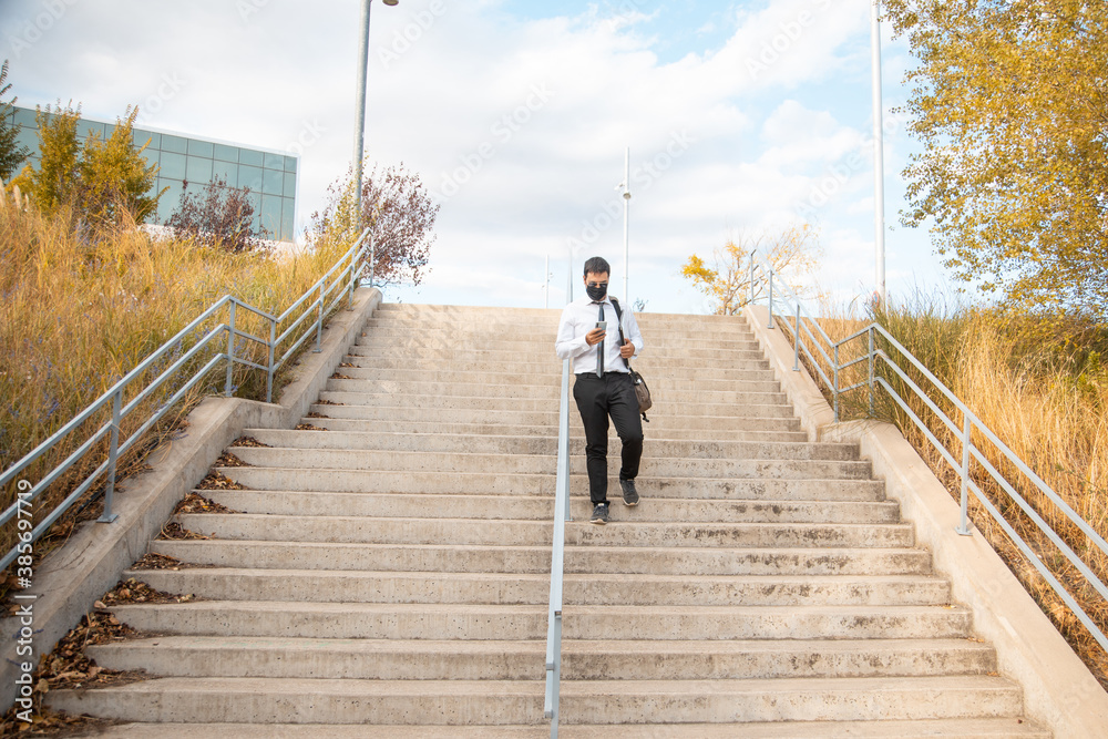 office man walking down park stairs with mask
