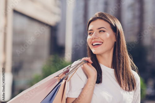 Photo portrait of laughing girl with shopping bags behind back outside