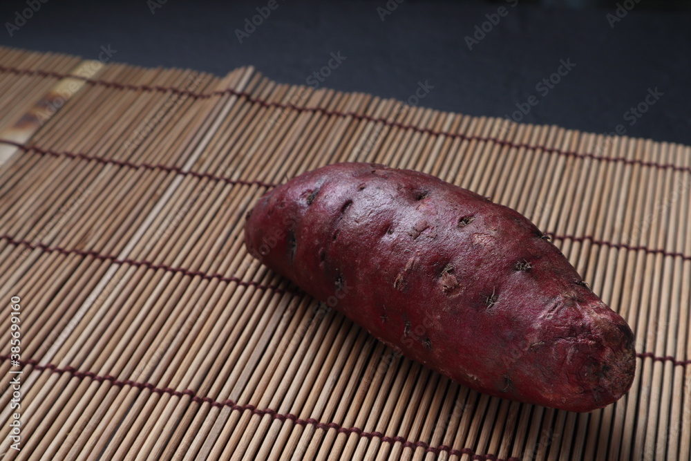 sweet purple potato plant is on the bamboo mat of the black wooden table in the kitchen sweet purple potato plant is on the bamboo mat of the black wooden table in the kitchen