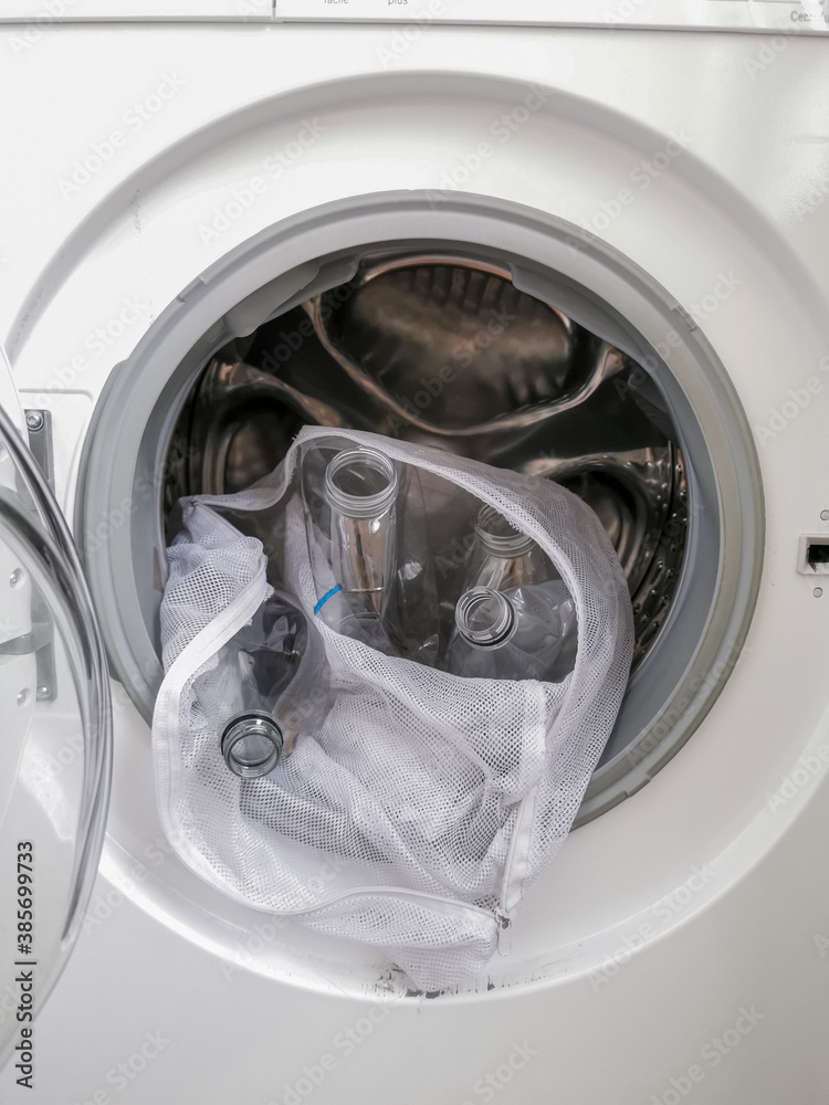 Washing machine filled with plastic bottles representing micro plastic waste pollution during laundry Washing machine filled with plastic bottles representing micro plastic waste pollution during laundry