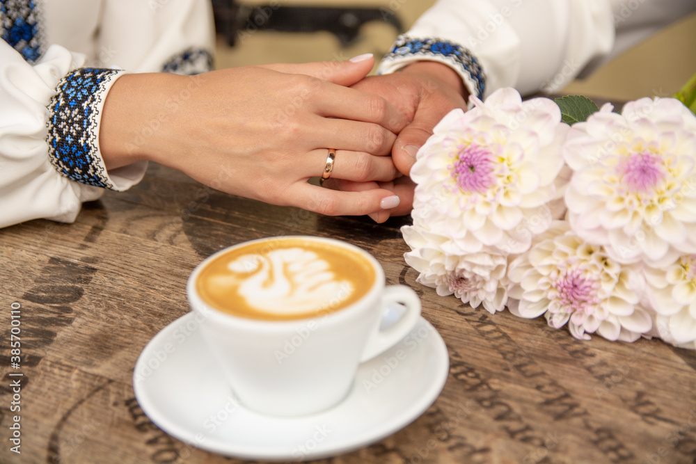 Wedding rings on the hands of brides. Fragrant, hot cappuccino on the table. Wedding rings on the hands of brides. Fragrant, hot cappuccino on the table.