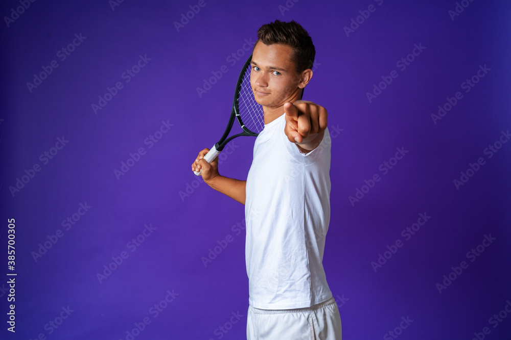 Caucasian young man tennis player posing with tennis racket against purple background Caucasian young man tennis player posing with tennis racket against purple background