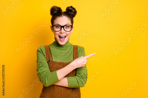 Photo of surprised girl point index finger copyspace indicate incredible sales adverts promotion recommend suggest select wear green pullover overall isolated bright shine color background
