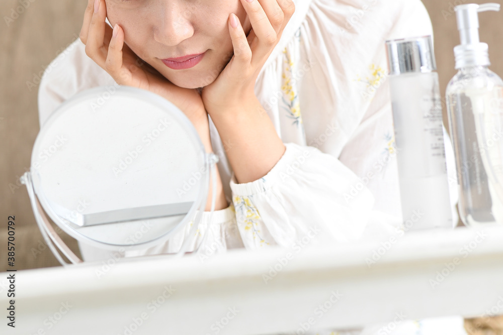 Naklejka premium 鏡を見ながら肌トラブルに悩む女性