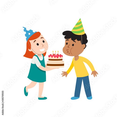 Happy group of children having fun at birthday party. Child blows out candles on cake.