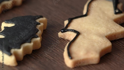 Close up of decorating cute Halloween bat sugar gingerbread cookies with frosting icing cream topping bag.