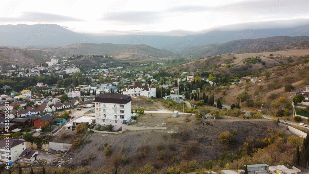 View from a height to the village of Malorechenskoye in the Crimea. Behind you can see the sunset behind the mountains, in front of many houses of the village