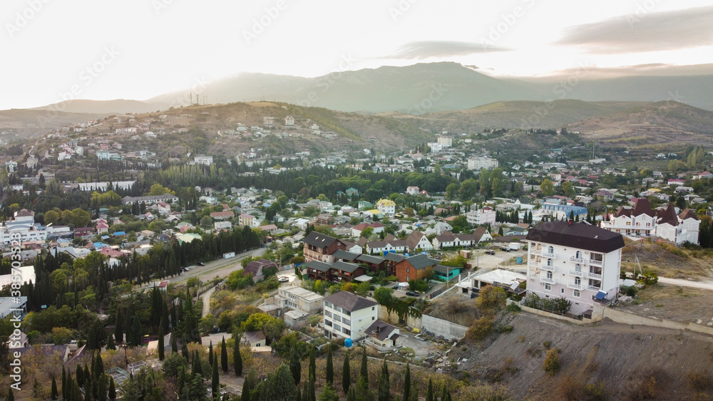 View from a height to the village of Malorechenskoye in the Crimea. Behind you can see the sunset behind the mountains, in front of many houses of the village