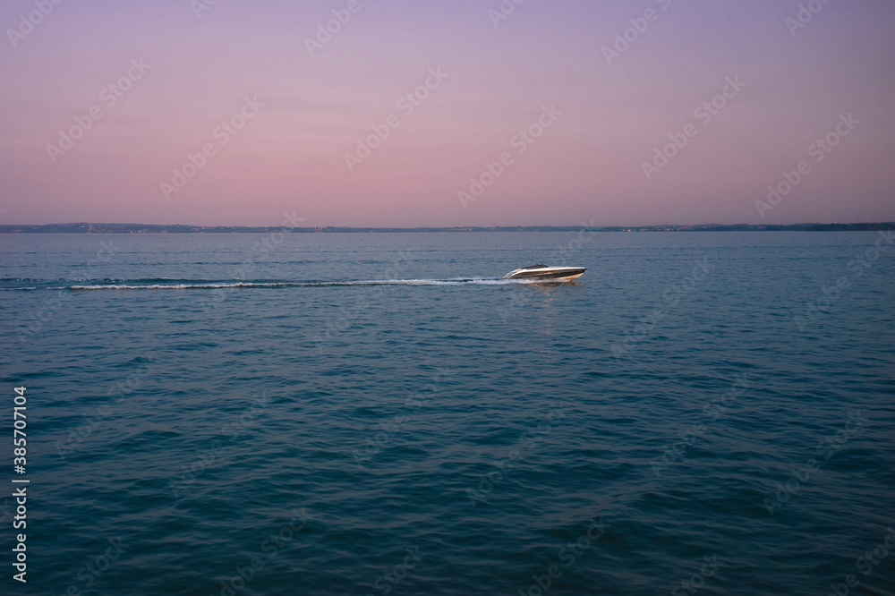 Large speedboat moving at high speed in the background of the coastline and sky. Drone view of a boat sailing. Travel - image. sunset
