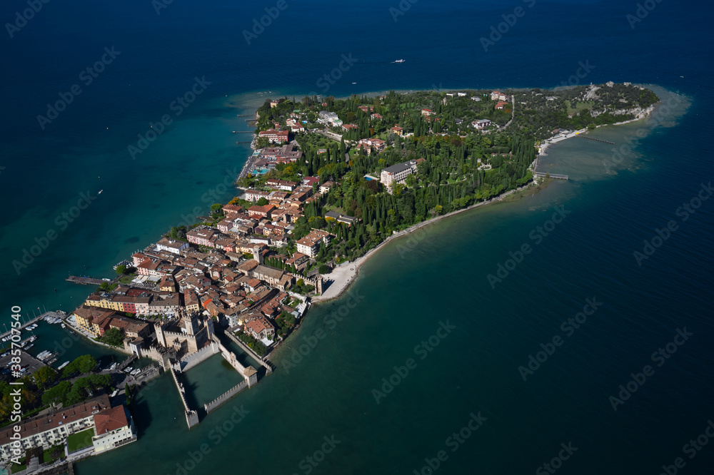 Autumn in Italy on Lake Garda, Sirmione peninsula. Aerial view to the town of Sirmione, popular travel destination on Lake Garda in Italy. Trees in the autumn season.