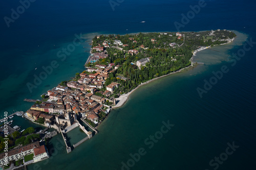 Autumn in Italy on Lake Garda, Sirmione peninsula. Aerial view to the town of Sirmione, popular travel destination on Lake Garda in Italy. Trees in the autumn season.