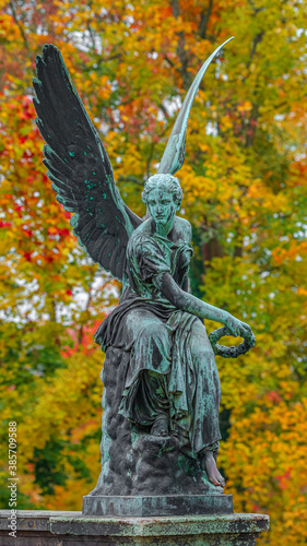 Statue of ancient beautiful winged angel in downtown park of Potsdam in beginning of Autumn at sunset, Germany
