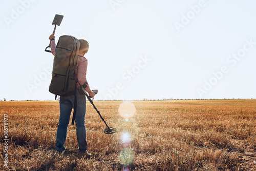 Man with metal detector equipment searching for metal goods in the field