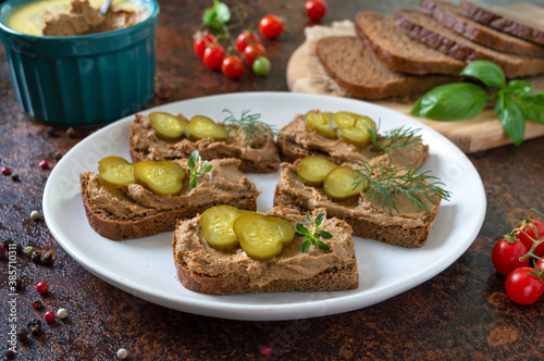 Canapes with chicken liver pate and pickled cucumbers on rye bread. Tasty and healthy appetizer.