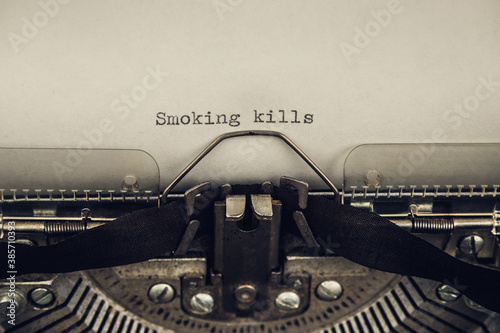 typing a warning slogan smoking kills on a vintage typewriter close-up. old and grunge atmosphere