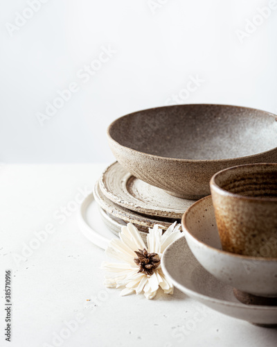 handicraft ceramics, empty craft ceramic bowl, plates and cup on light background 