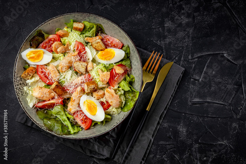 Caesar salad with chicken on a black background top view