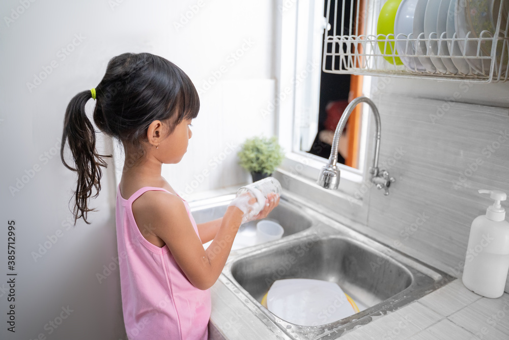 kid washing the dishes. helpful young girl doing clean up at home kid washing the dishes. helpful young girl doing clean up at home