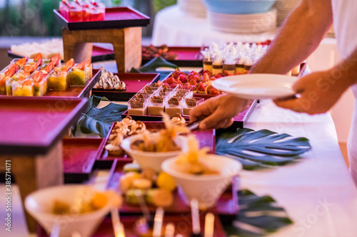 Close up of man serving food in catering table during event - wedding and party concept dinner with cakes and delicious -