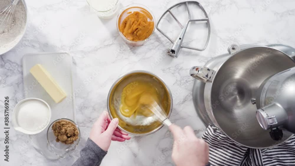 Time lapse. Flat lay. Mixing ingredients in electric kitchen mixer to bake pumpkin spice cupcake.