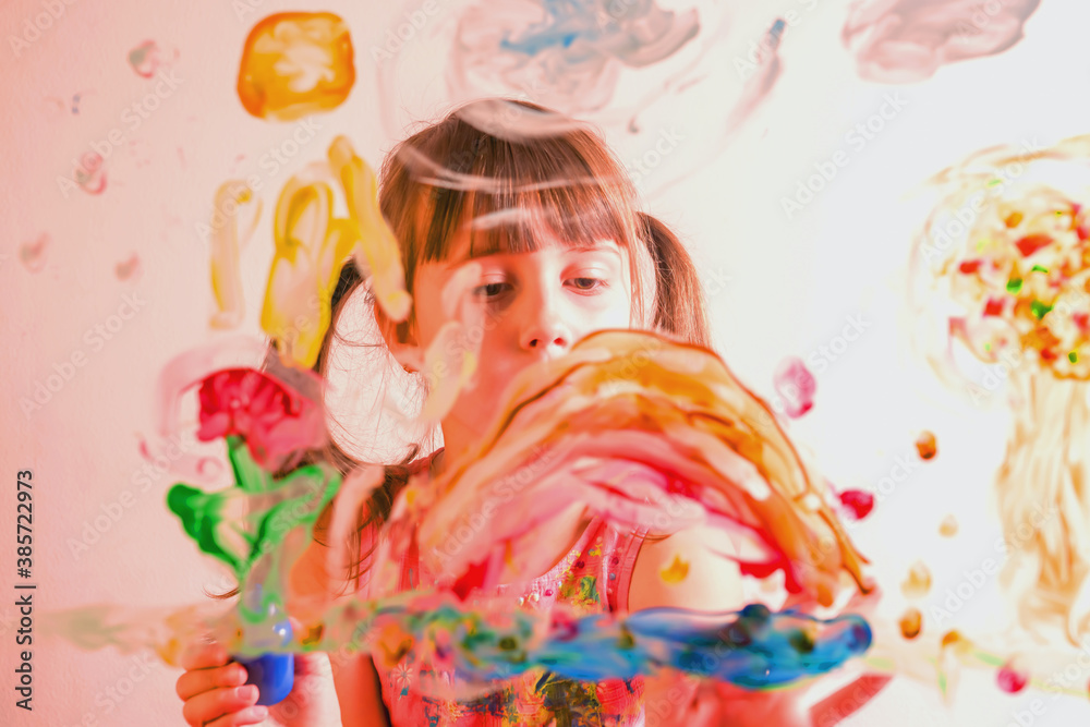 Beautiful young girl painting on glass with colorful finger. Happy childhood, art, painting lessons concept. Beautiful young girl painting on glass with colorful finger. Happy childhood, art, painting lessons concept.