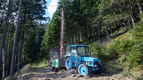 Blue tractor in a forest working as a cable car for wood transport.