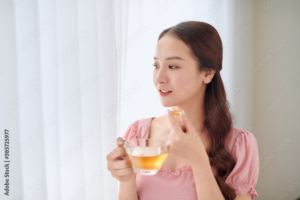 Portrait of young Asian woman eating vitamin pill for health care at home. Portrait of young Asian woman eating vitamin pill for health care at home.