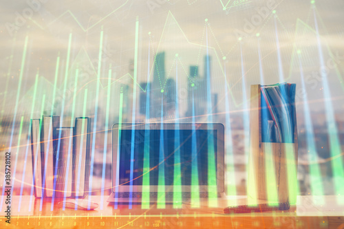 Stock market graph on background with desk and personal computer. Multi exposure. Concept of financial analysis.