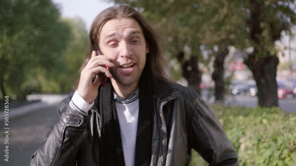 Cheerful talking and loud laughter of an attractive guy on the cell phone at the street. Concept of people and emotions. Cheerful talking and loud laughter of an attractive guy on the cell phone at the street. Concept of people and emotions.