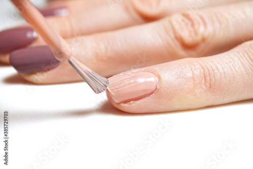 Manicure. Closeup of a woman hand polishing nails manicure. Nail technician manicure at nail salon. Young caucasian woman receiving a french manicure.