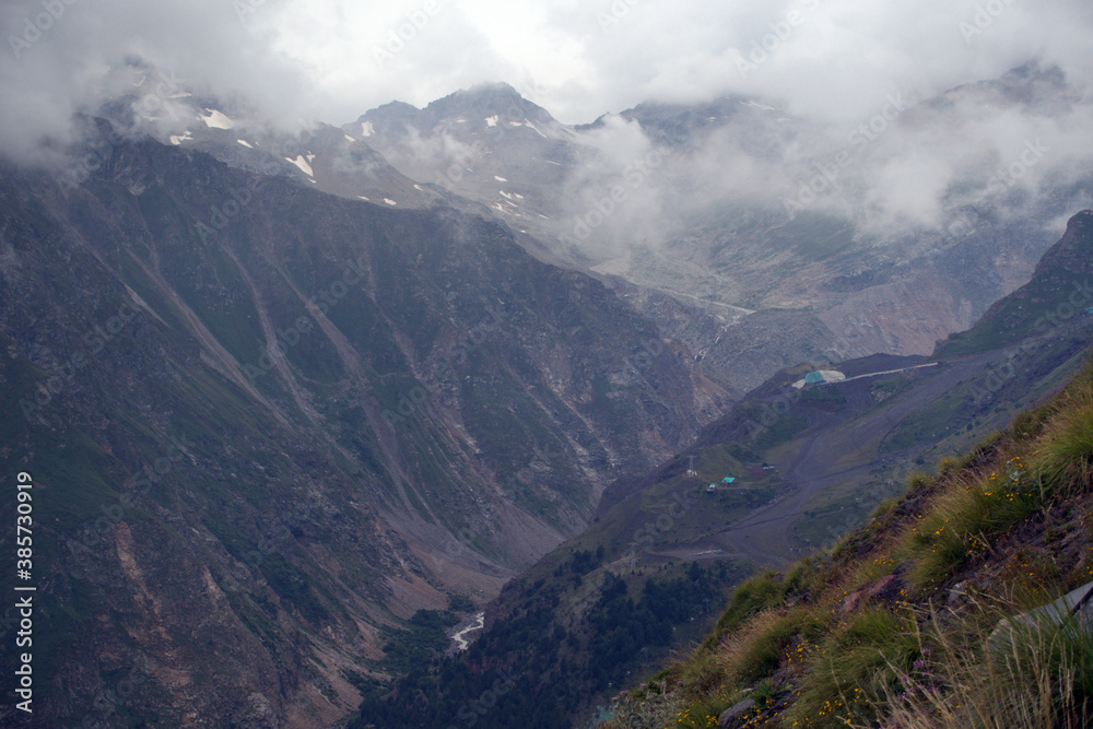 Peaks and slopes of mountains in foggy weather. Elbrus region near the village of Terskol. Caucasus, Russia.