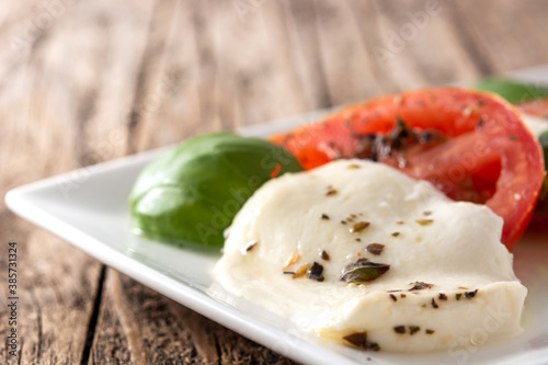 Traditional caprese salad with tomato and mozzarella cheese on wooden table