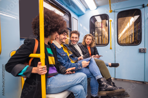 Group of four multiethnic people traveling subway using smartphone - Group of friends multiracial talking together using smartphone