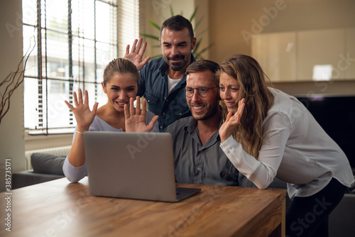 Authentic shot of young happy college friends are making a video call to relatives or friends with laptop in a living room at home.