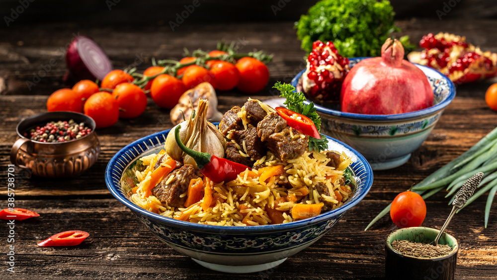 Traditional uzbek meal called pilaf. Rice with meat, carrot and onion in plate with oriental ornament, Uzbek oriental cuisine. Long banner format. space for text