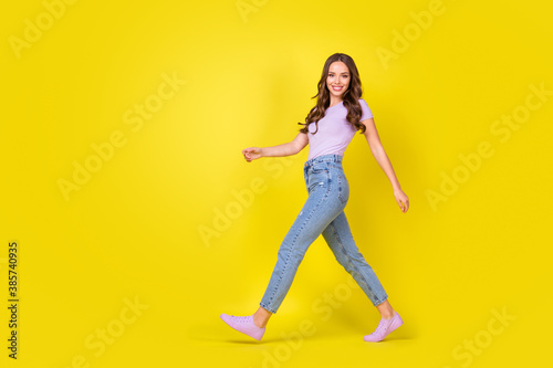 Full length body size profile side view of attractive thin cheerful wavy-haired girl going isolated over bright yellow color background